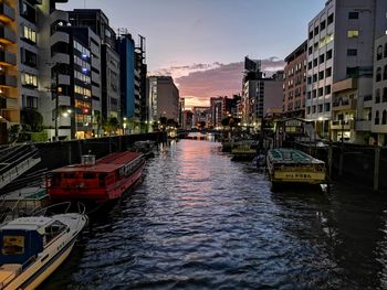 Canal amidst buildings in city against sky during sunset