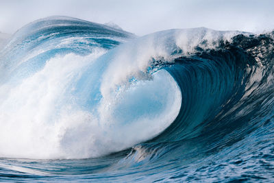 Powerful foamy sea waves rolling and splashing over water surface against cloudy blue sky