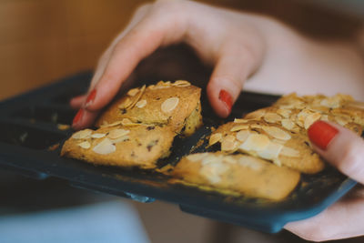 Cropped hands of woman holding cookies in tray