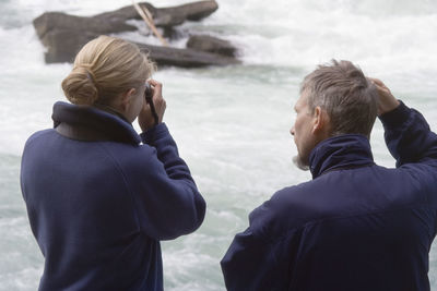 Rear view of father and daughter standing by fraser river