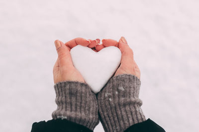 Close-up of woman hand holding heart shape in winter