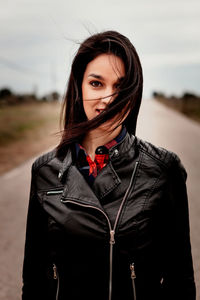 Portrait of young woman standing against black background