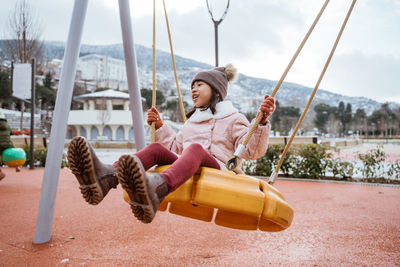 Portrait of young woman sitting on swing at playground