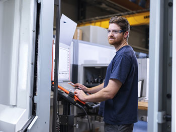 Apprentice engineer operating cnc machine in factory