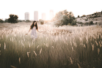 Young woman walking amidst plants on field