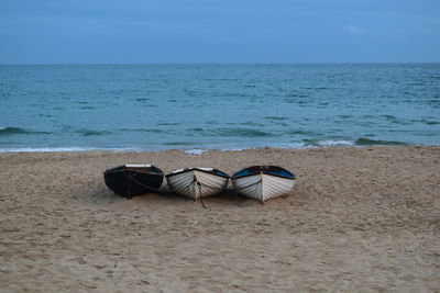 Boats on shore at beach against sky