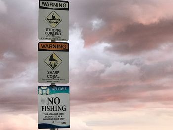 Close-up of warning sign against sky