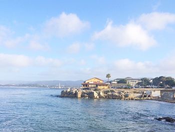 Buildings by sea against sky