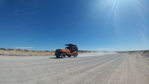 Car on desert against blue sky