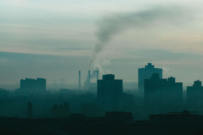 Smoke emitting from factory against sky