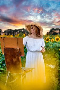 Woman standing on field against sky during sunset