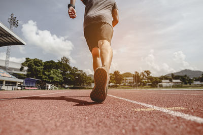 Low section of man running on sports track