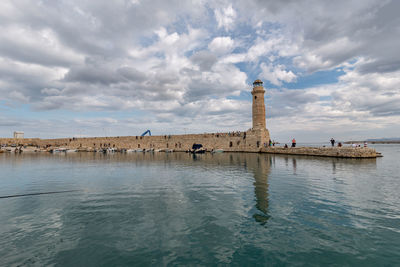 Lighthouse by sea against sky