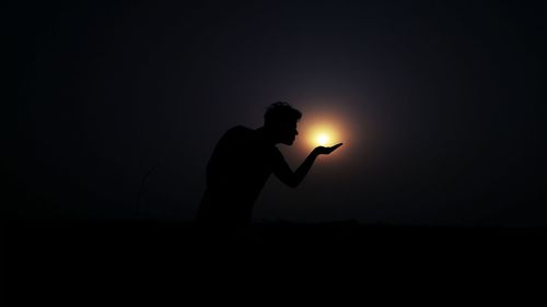 Silhouette man standing against sun during sunset