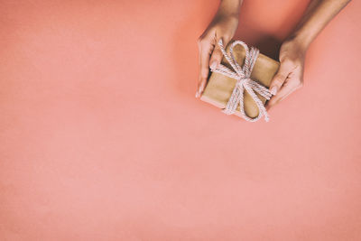 Cropped hands of woman holding gift on orange table