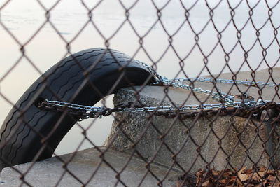 Close-up of chain tied up on chainlink fence