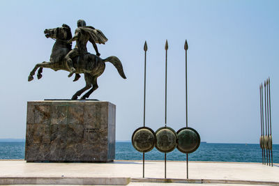 Statue by sea against clear sky