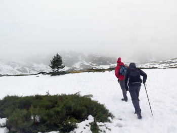 Rear view of people on snow covered mountain against sky