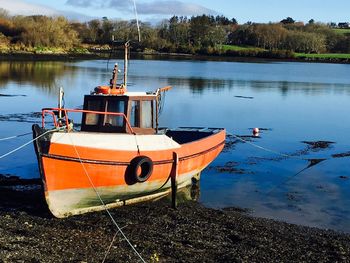 Boat moored on lake against sky