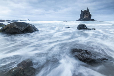 Rock formation in sea against sky