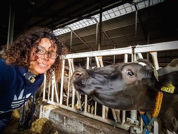 Portrait of woman by cow in pen