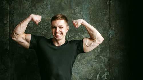 Close-up portrait of muscular man flexing muscles by wall