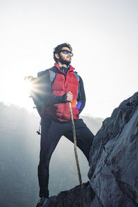 Young indian traveler boy trekking over a rocky mountain, standing on the top of the mountain.