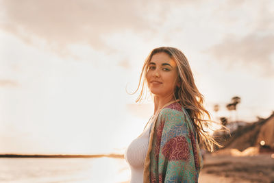 Portrait of young woman standing against sky