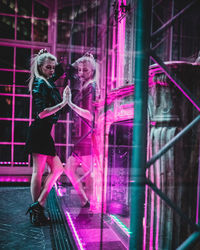 Woman standing by glass window at night