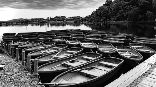 Row of boats moored at lakeshore against sky