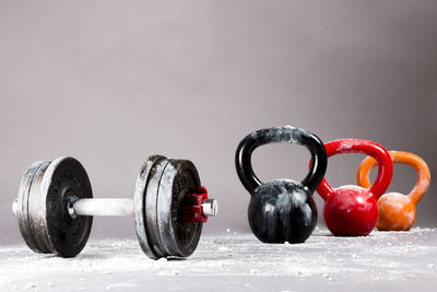 Close-up of dumbbell with colorful kettlebells against gray background