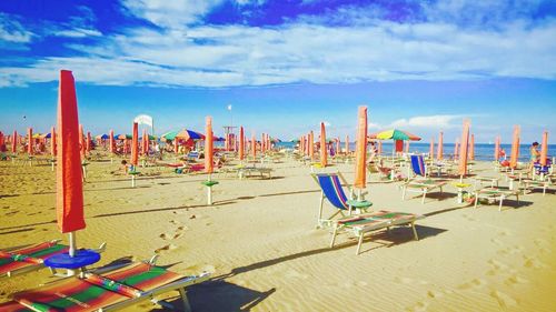 Row of chairs on beach against blue sky