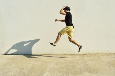 Full length of man jumping by wall