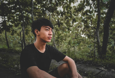 Young man looking away in forest