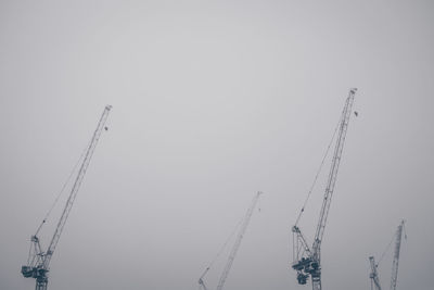 Low angle view of cranes against clear sky