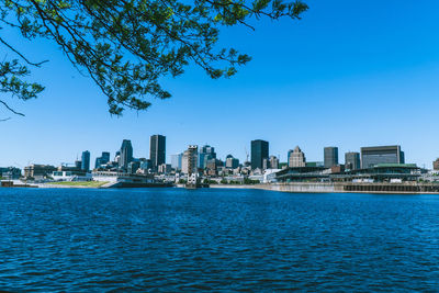 Sea by buildings against clear blue sky