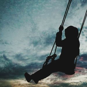 Silhouette man holding rope against sky