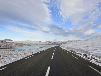 Empty asphalt road through snow covered landscape in iceland