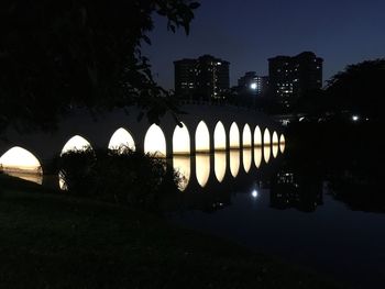 Illuminated bridge over river against sky at night