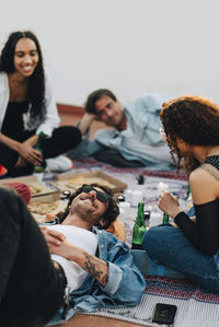 Group of male and female friends enjoying food and drinks at rooftop party