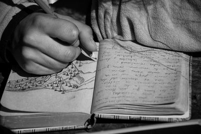 Cropped image of woman writing in book