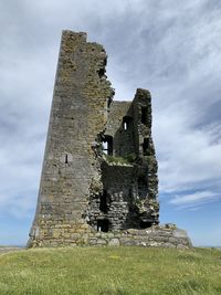 Low angle view of old building on field against sky