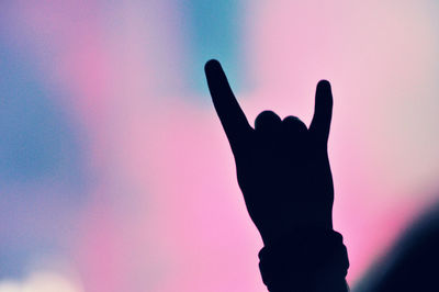 Close-up of silhouette hand gesturing horn sign during concert