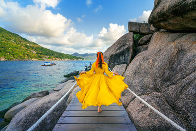 Rear view of woman on rock against sky