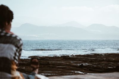 Rear view of man looking at sea against sky