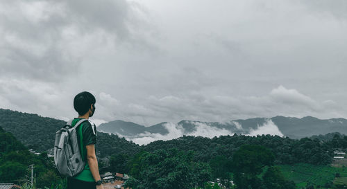 Rear view of man standing on mountain against sky