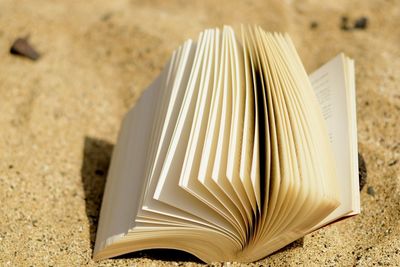 High angle view of open book on sand