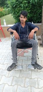 Full length portrait of young man sitting on chair