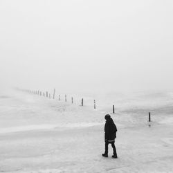 Woman walking on snowy field during foggy weather