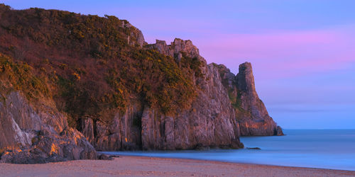 Rock formations by sea against mountain